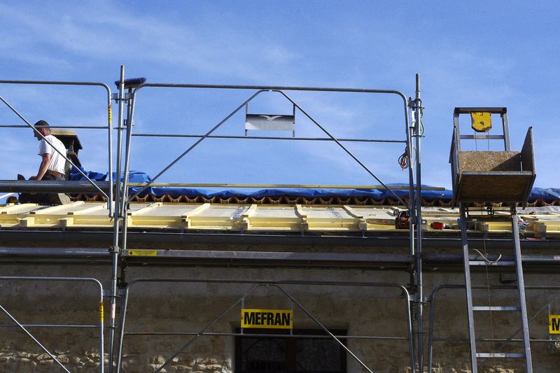 Roofers re-roofing a house from scaffolding