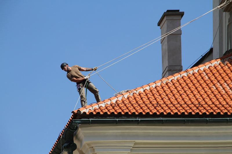 Roofer roped on to a steep tile roof