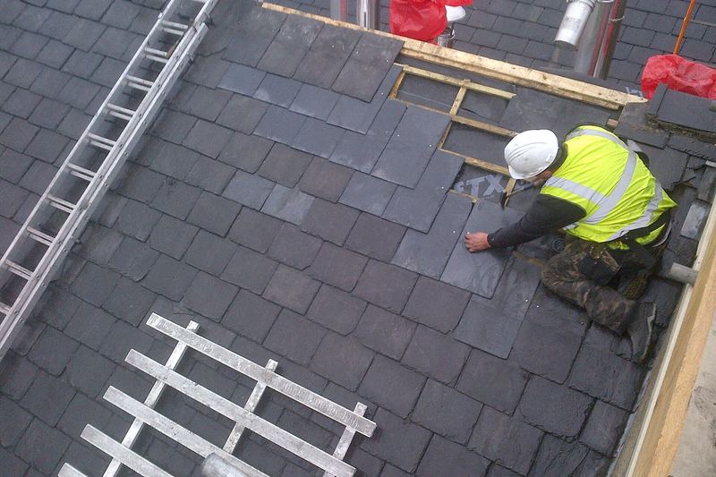 Roofer laying Welsh slate on a pitched roof